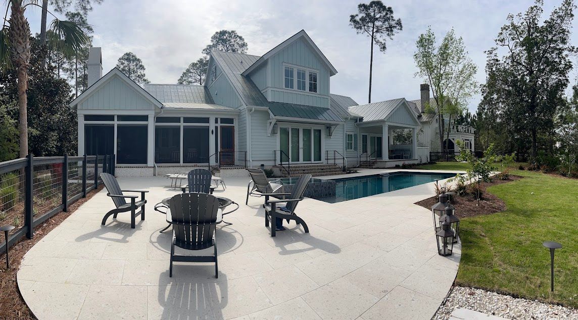 A large house with a swimming pool and patio furniture in front of it.