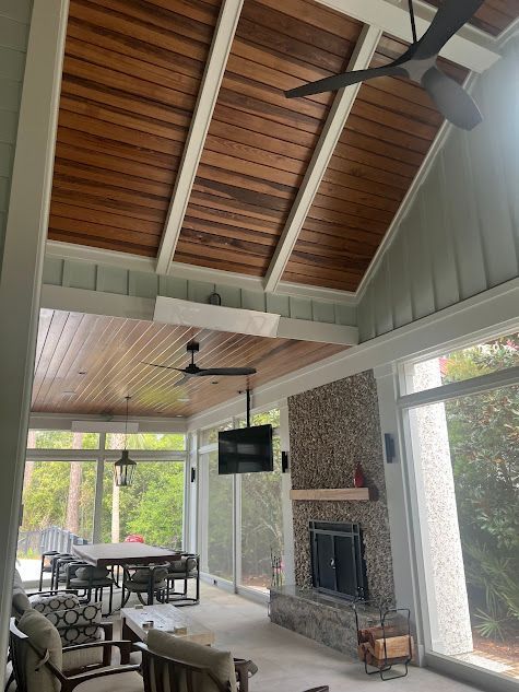 A living room with a wooden ceiling and a fireplace.