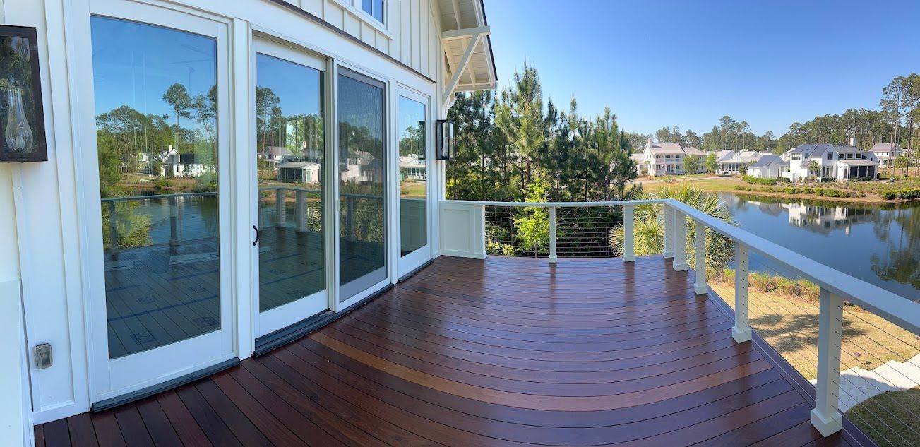 A large wooden deck with sliding glass doors overlooking a lake.