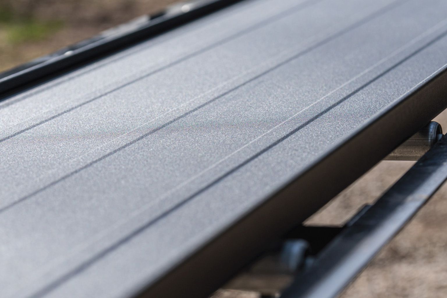 Green cabin with burgundy trim, a brown metal roof, and copper gutters, surrounded by trees.