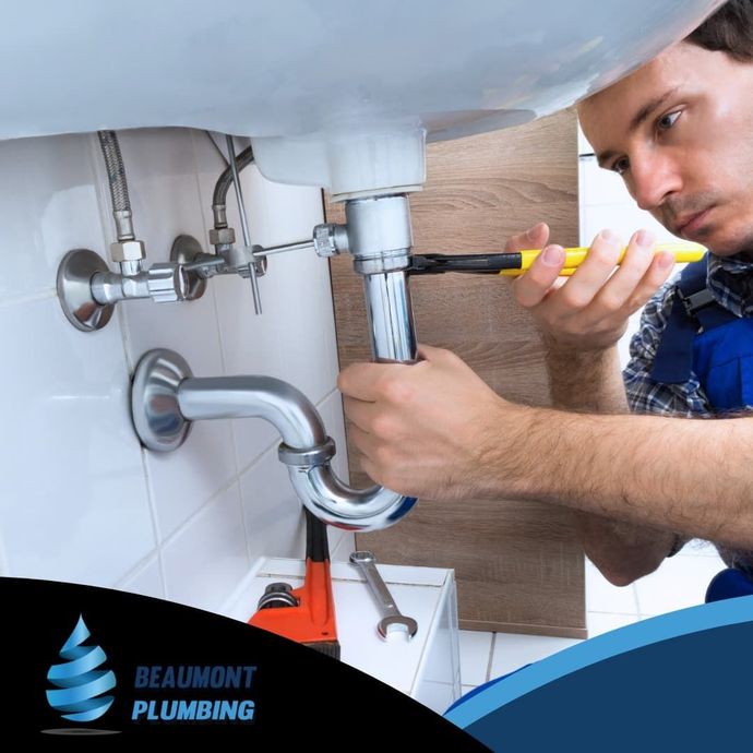 A Man is Fixing a Sink Pipe With a Wrench — Beaumont Plumbing in Glenfield Park, NSW