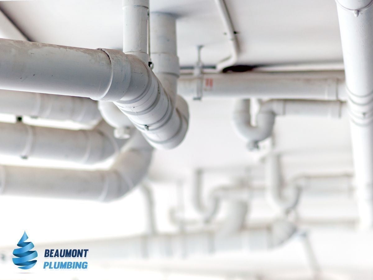 A bunch of white pipes are hanging from the ceiling — Beaumont Plumbing in Glenfield Park, NSW