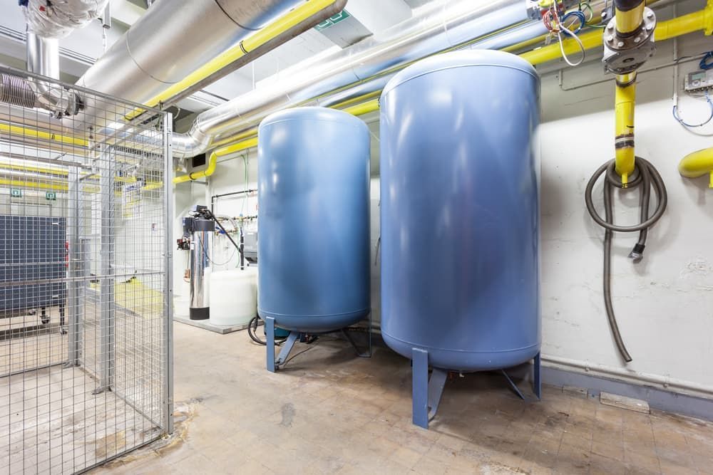 Two Blue Tanks Are Sitting Next to Each Other in a Room — Beaumont Plumbing in Glenfield Park, NSW