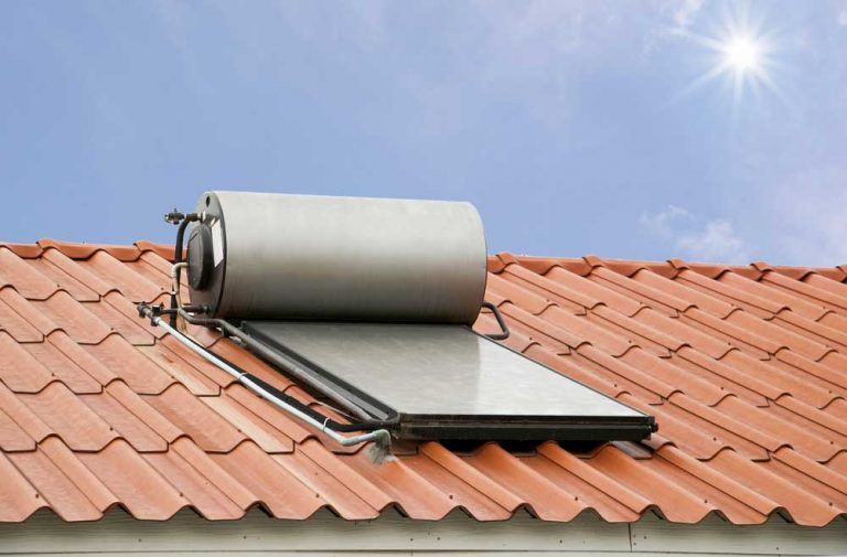 A Solar Water Heater is Sitting on Top of a Tiled Roof — Beaumont Plumbing in Glenfield Park, NSW