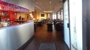 Un long couloir menant à un restaurant avec un bar et des tables.