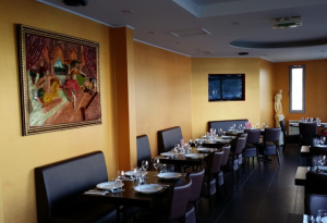 Un restaurant avec des tables et des chaises et un tableau au mur