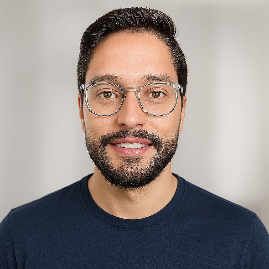 Man with glasses smiles, wearing a blue shirt.