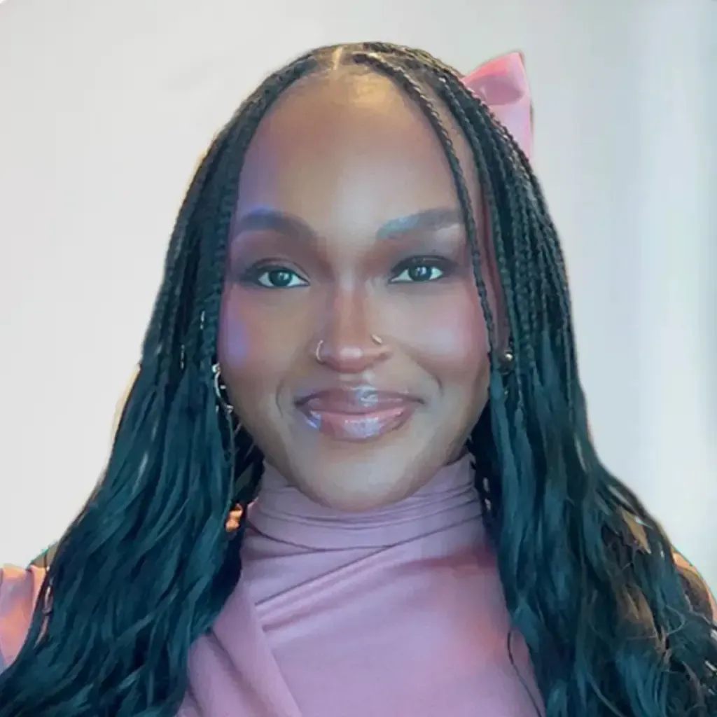Woman with long braided hair, wearing a teal shirt, smiling at the camera.