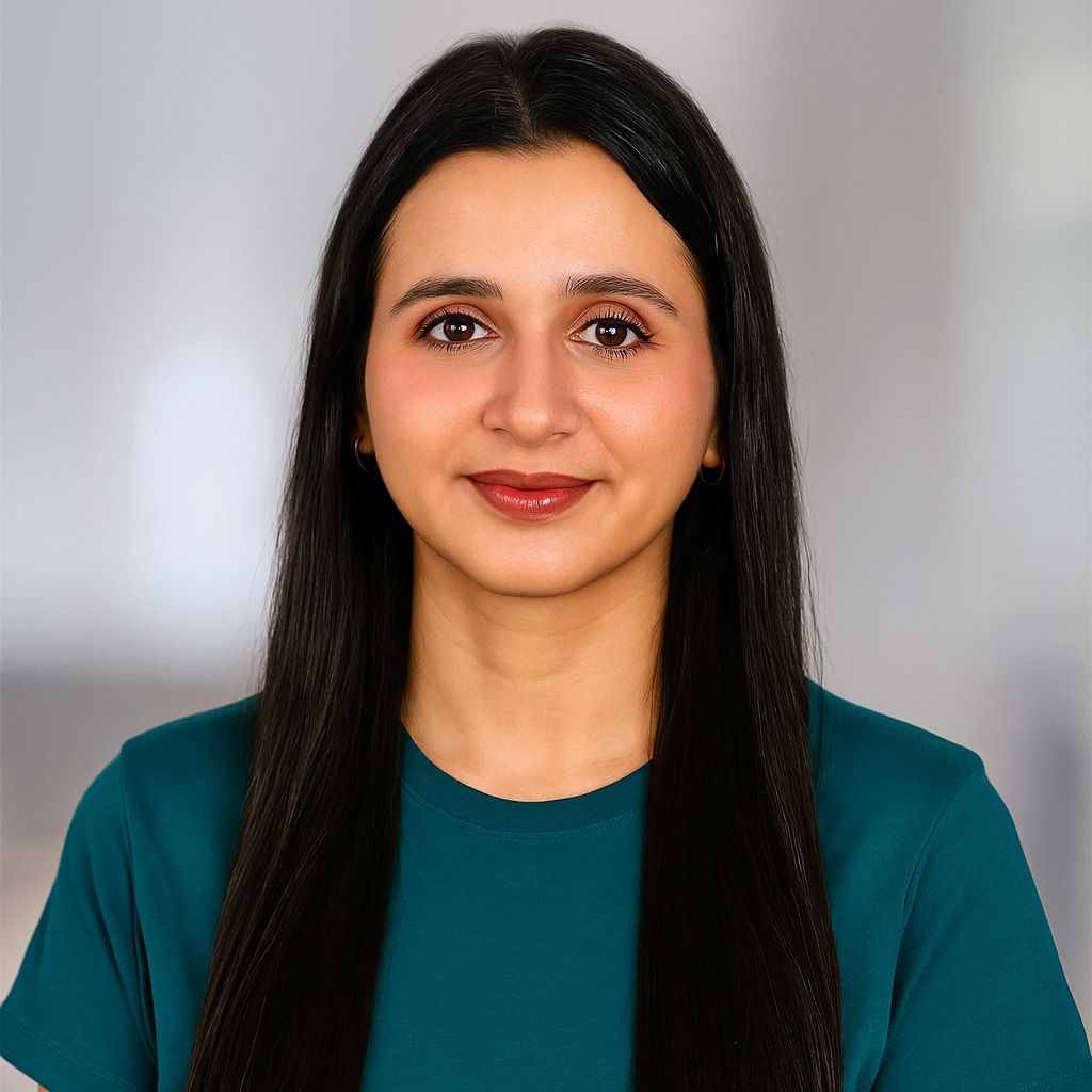 Woman with long, dark hair wearing a teal shirt smiles at the camera.