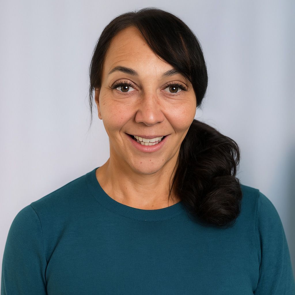 Woman with dark hair, smiling, wearing a teal sweater, in front of a neutral background.