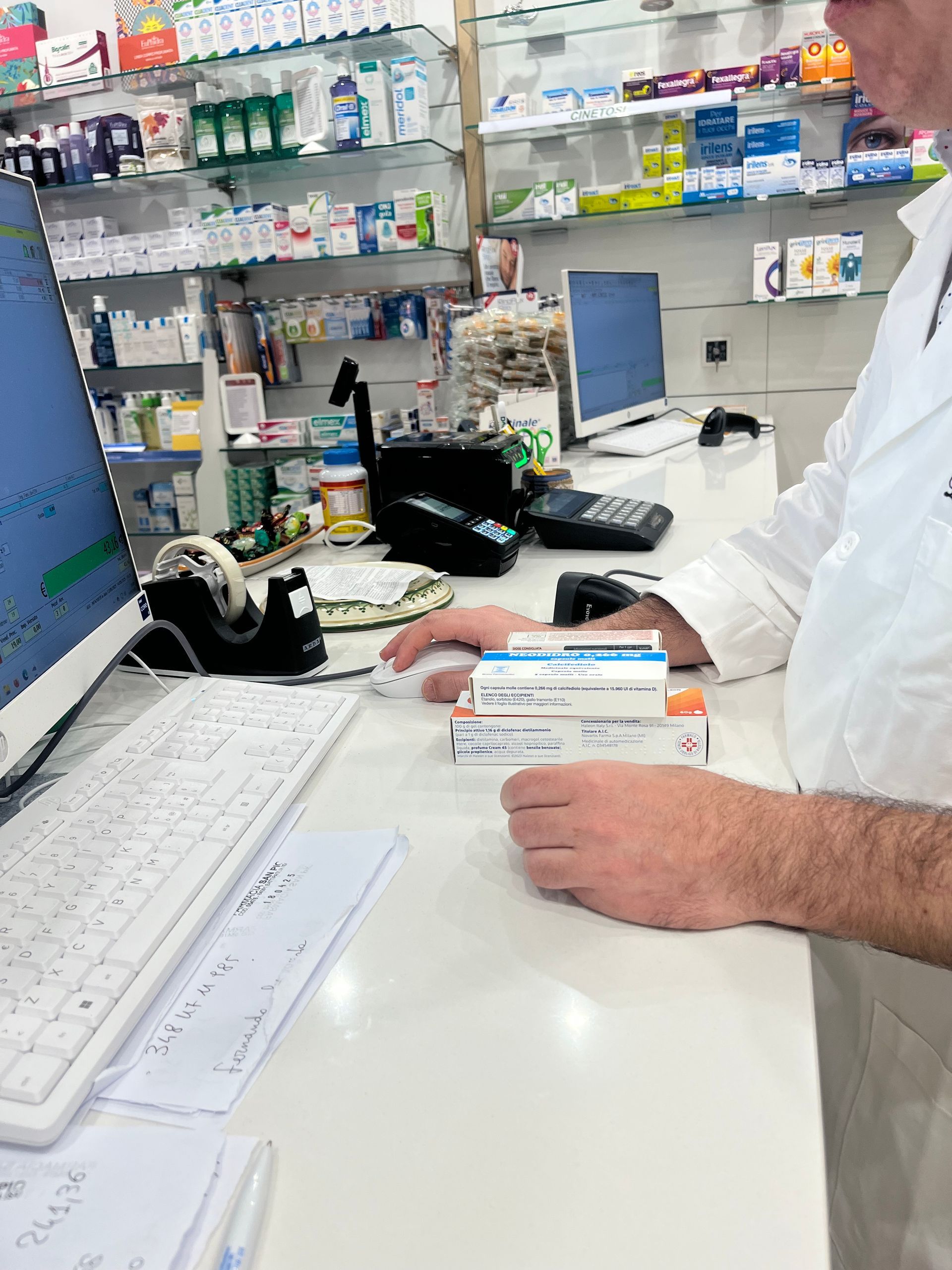 Un uomo è seduto alla scrivania davanti a un computer in una farmacia.