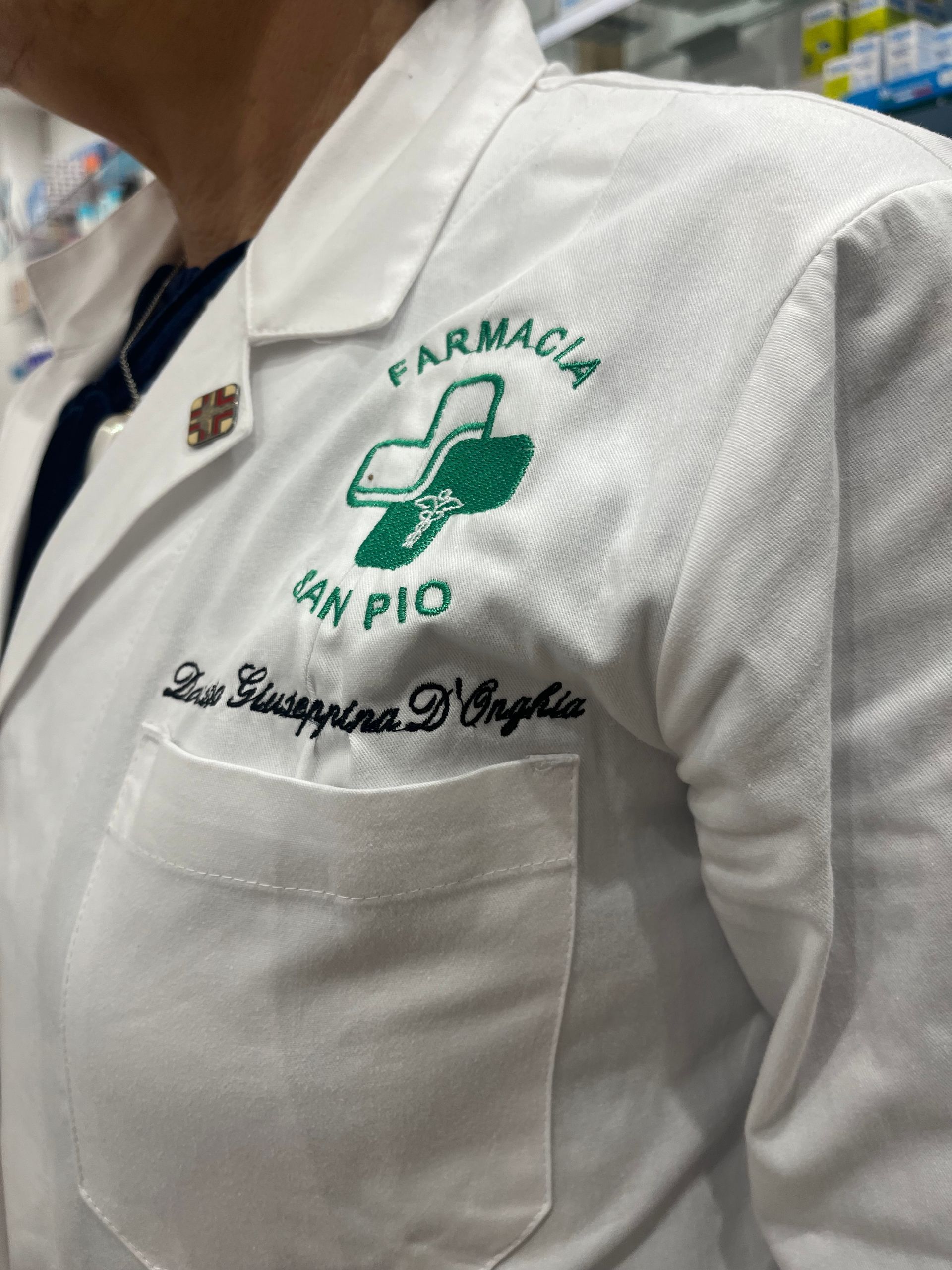 Un primo piano di una persona che indossa un camice da laboratorio con la scritta 