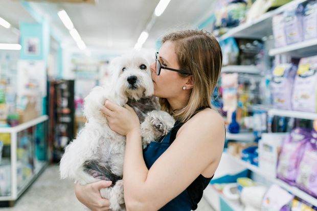 Una donna sta baciando un cagnolino bianco in un negozio di animali.