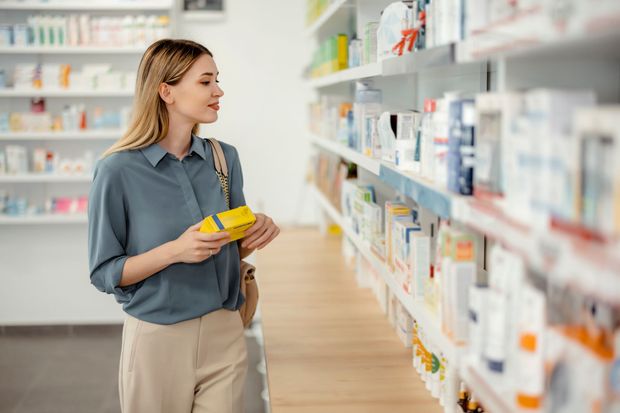 Una donna sta guardando una scatola di pillole in una farmacia.