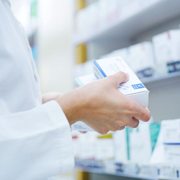 Un farmacista tiene in mano una scatola di pillole in una farmacia.