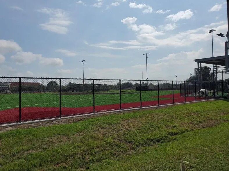 A baseball field with a fence around it on a sunny day