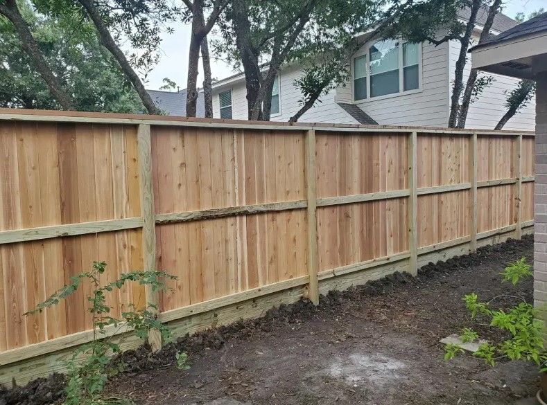 A wooden fence is in the backyard of a house.
