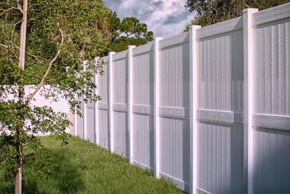 A white fence is surrounded by green grass and trees.