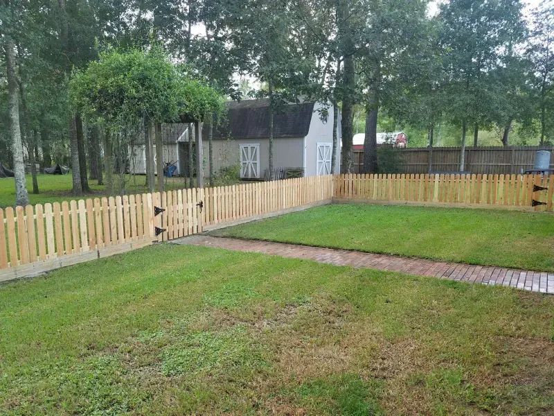 A wooden picket fence surrounds a lush green yard.