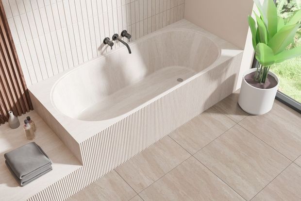 Bathtub in a light-colored bathroom with patterned walls and floor, a plant, and towels.