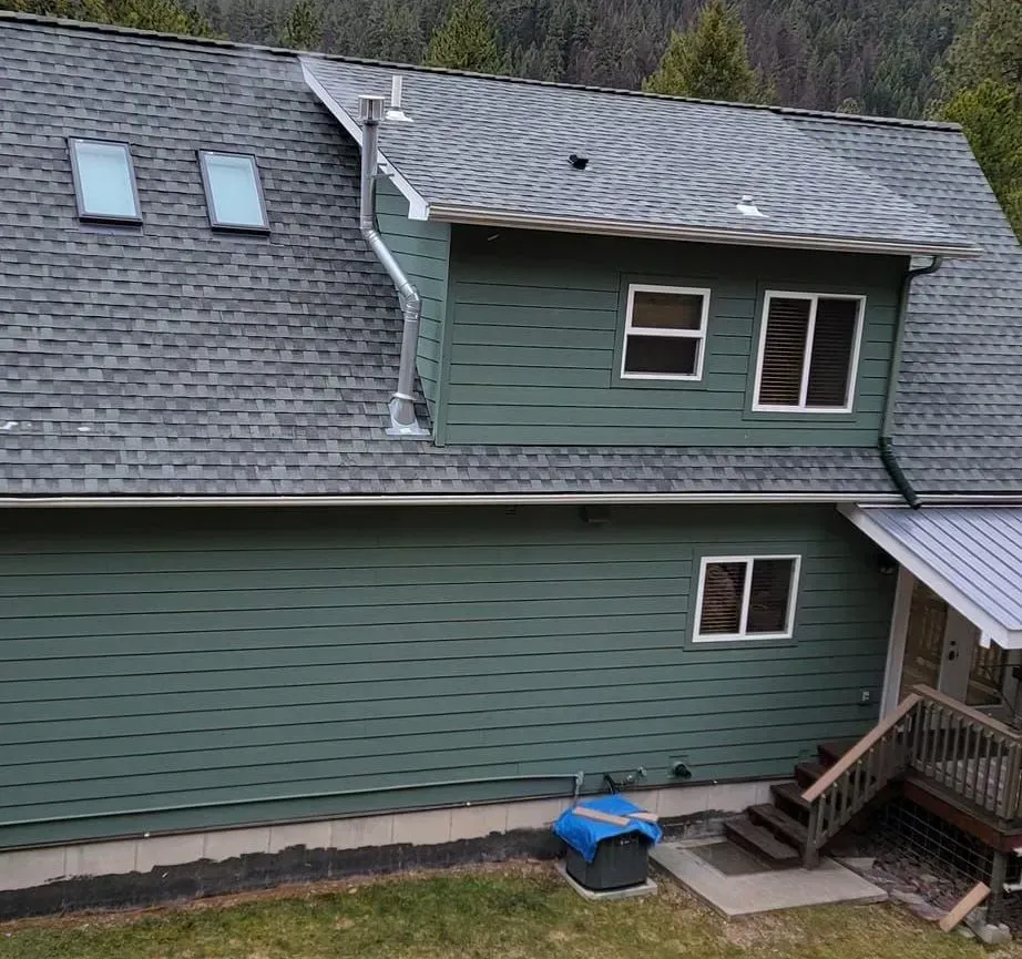 An aerial view of a green house with a gray roof