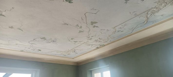 A room with a ceiling that is covered in mold and peeling paint.