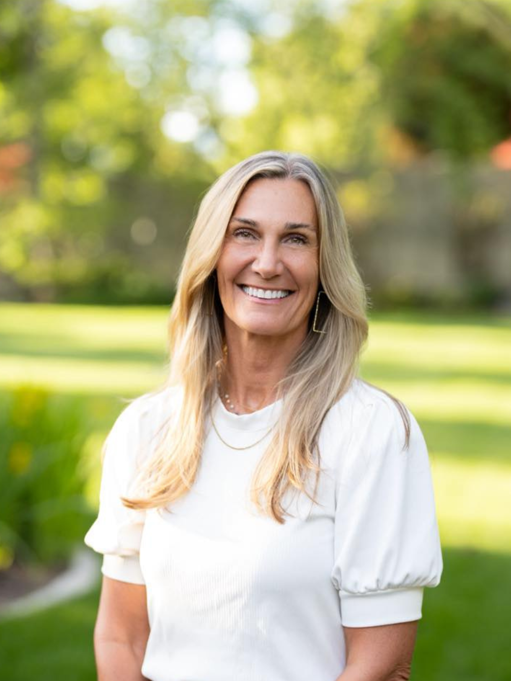 A woman in a black jacket is smiling for the camera