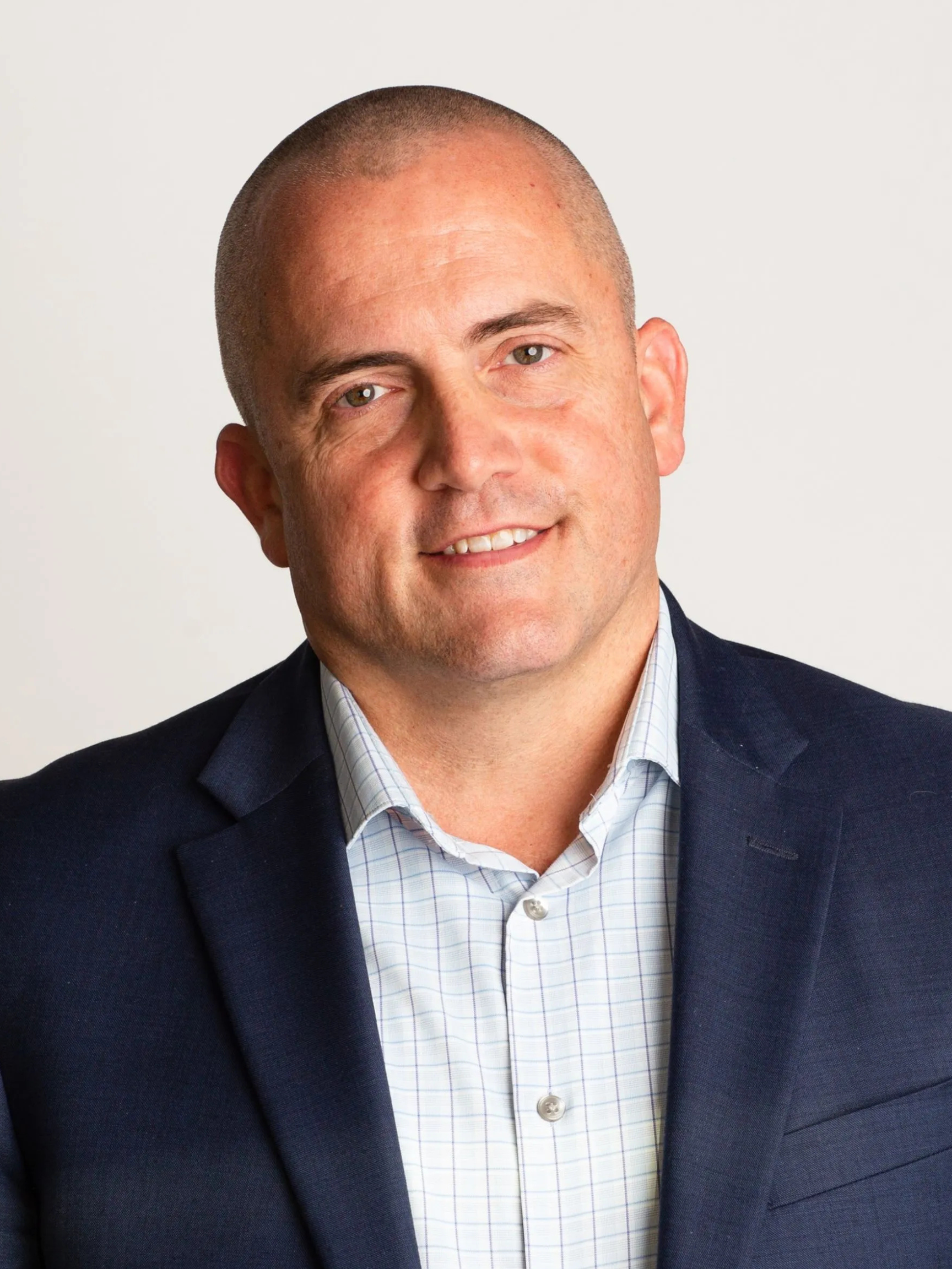 A man in a blue suit and white shirt is smiling for the camera.