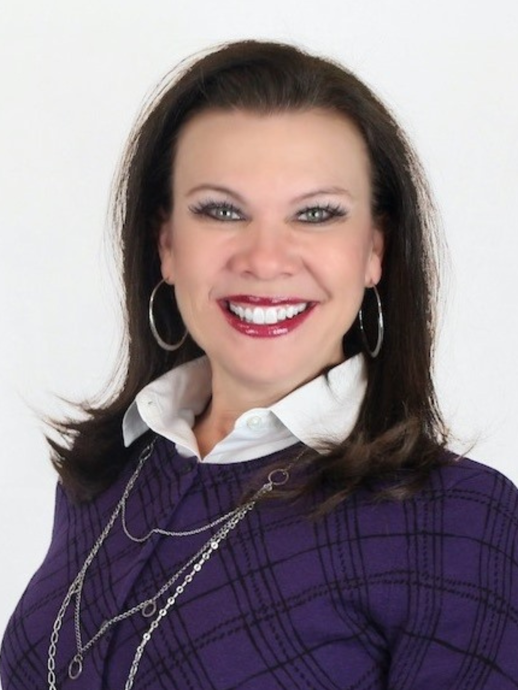 A woman wearing a purple plaid sweater is smiling for the camera