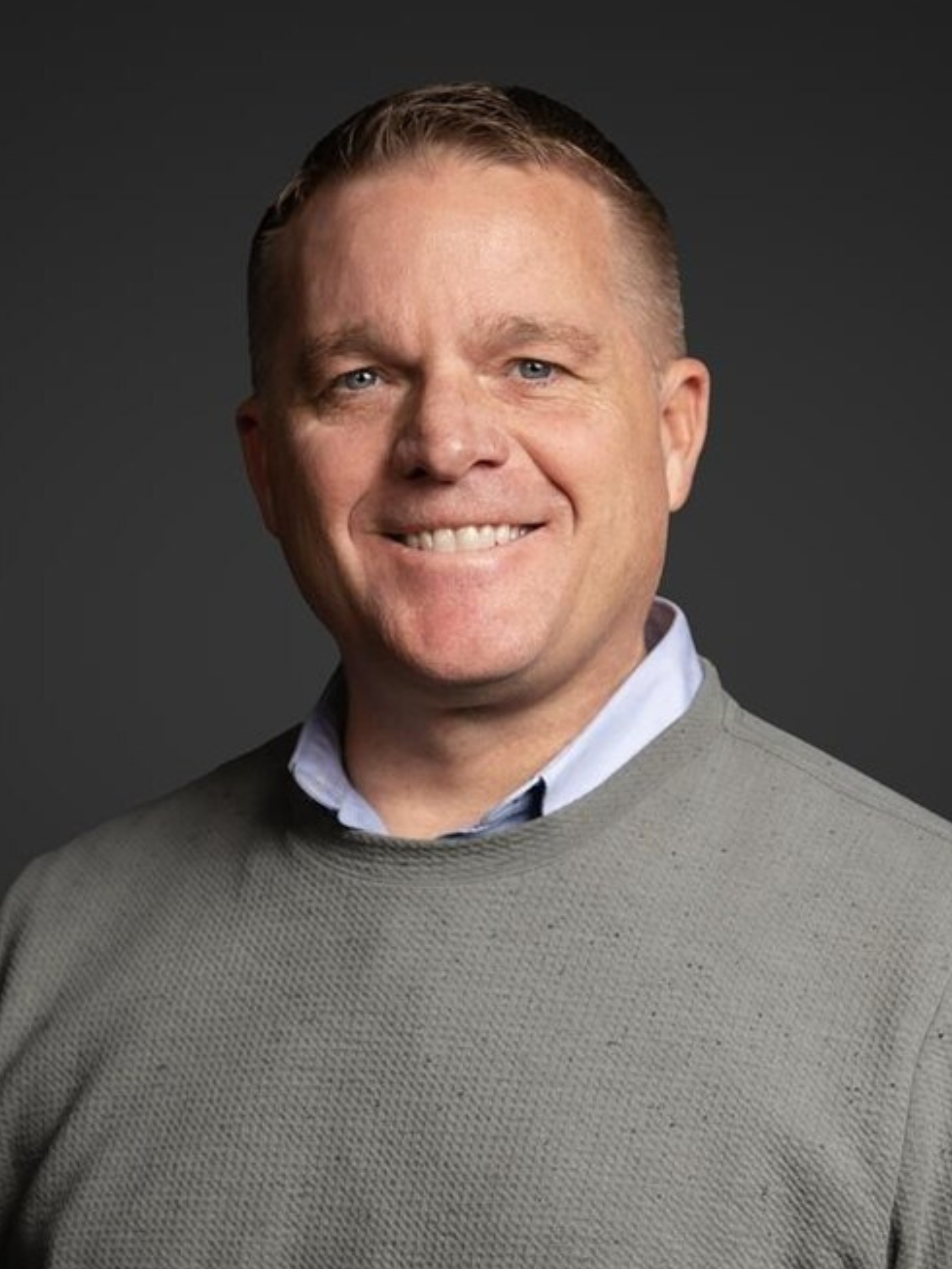 A black and white photo of a woman smiling in a sweater.