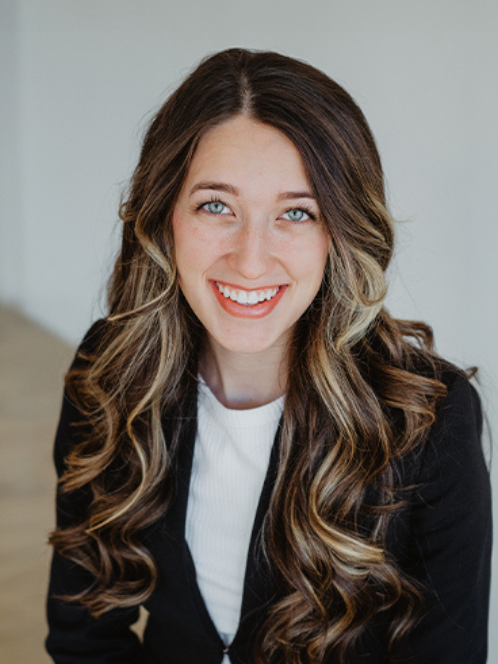 A woman with long blonde hair and blue eyes is smiling for the camera.