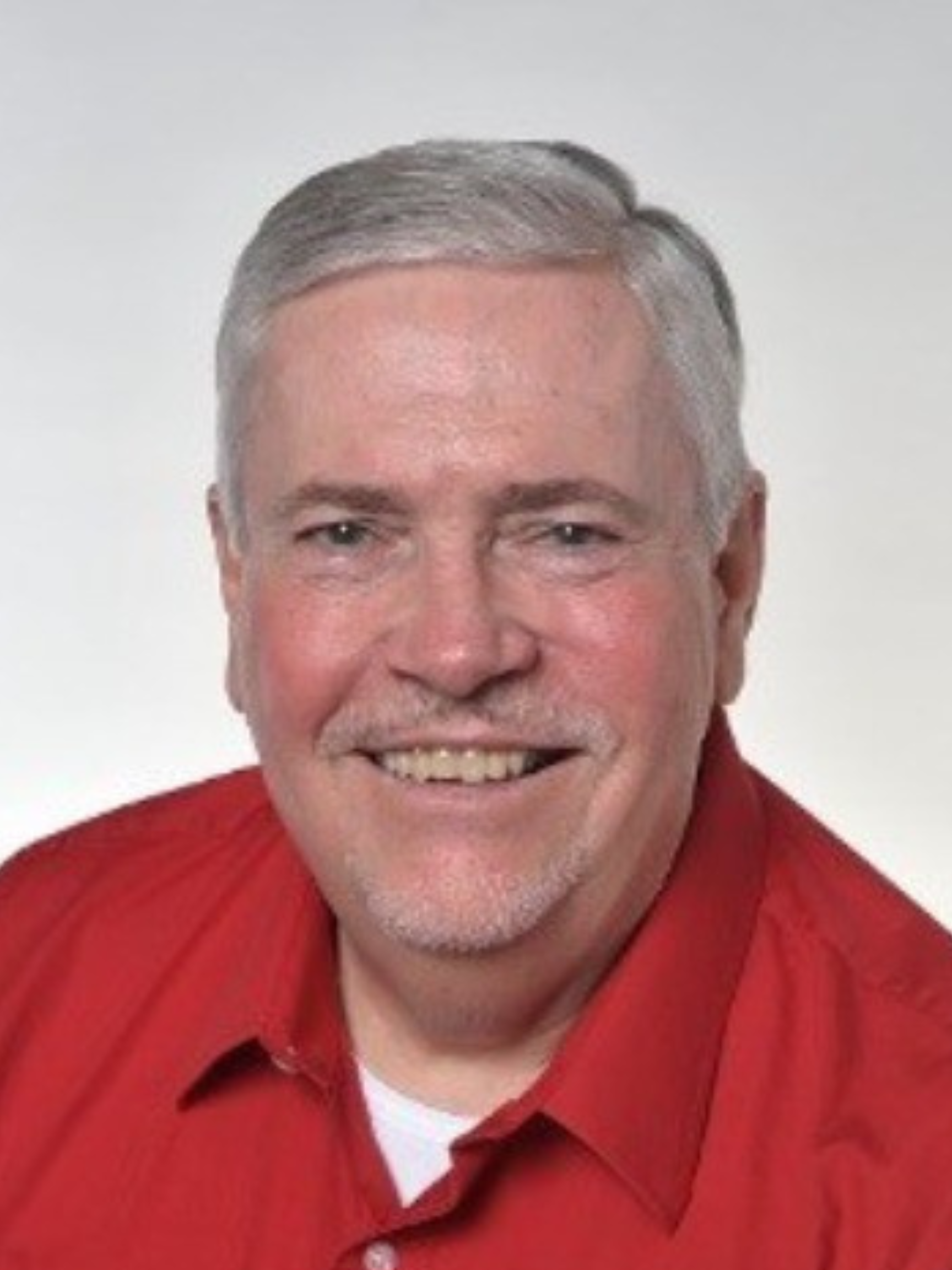 A man wearing glasses and a white shirt is smiling for the camera.