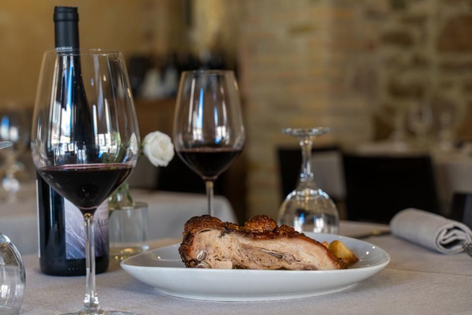 un piatto di cucina romana con due calici di vino rosso