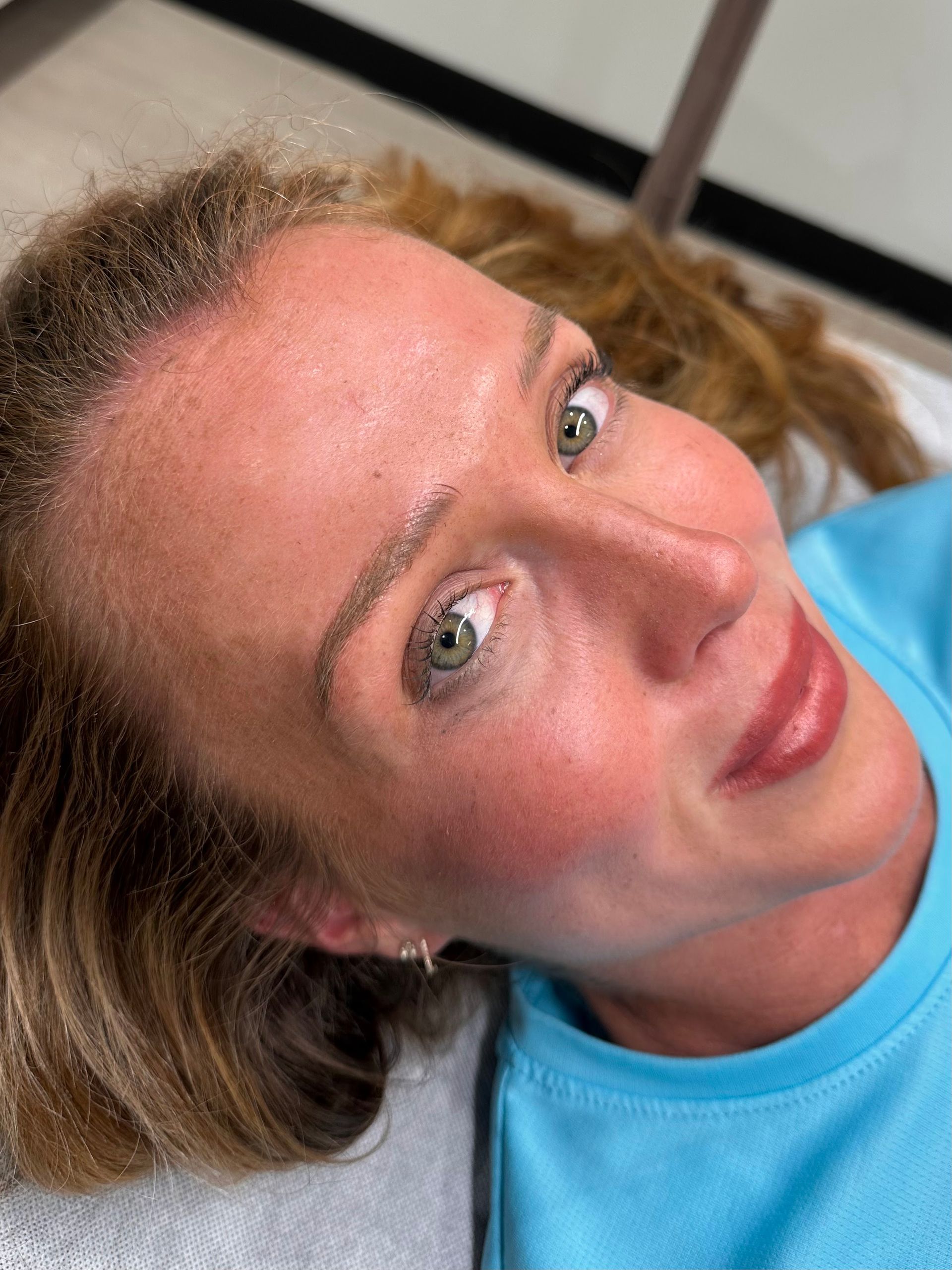A woman in a blue shirt is laying on a bed.