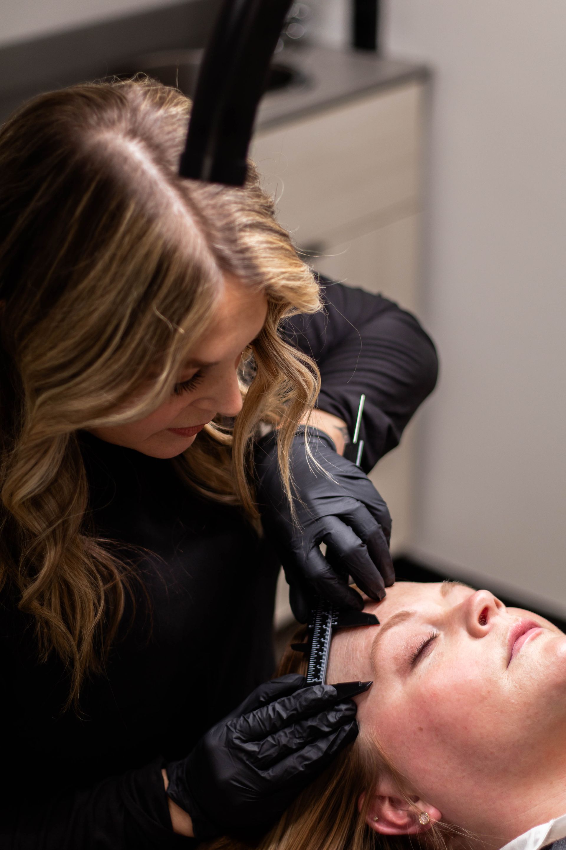 A woman is getting her eyebrows done by a woman in a salon.