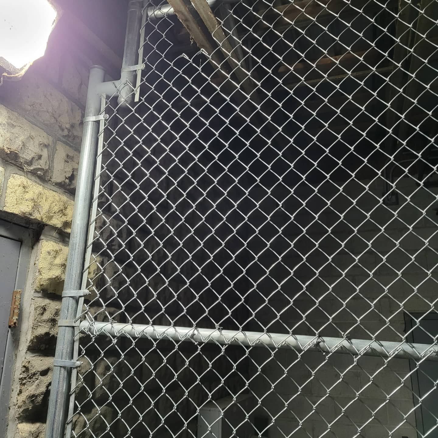 Chain-link fence gate next to a brick building.