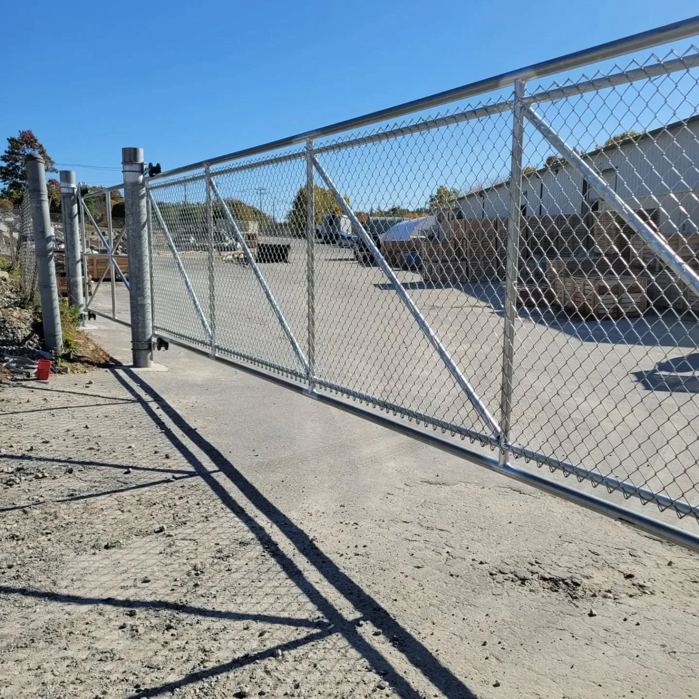 Chain link fence with a large sliding gate on concrete.