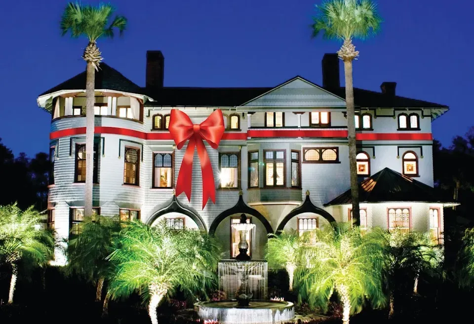 A large house decorated for christmas with a red bow