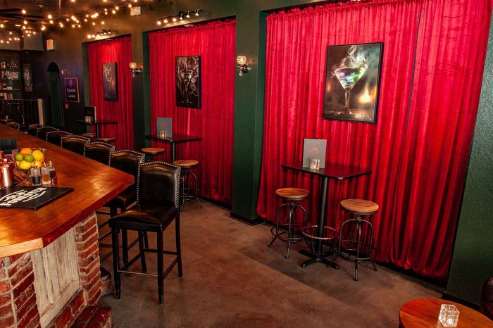 A bar with red curtains and tables and chairs.