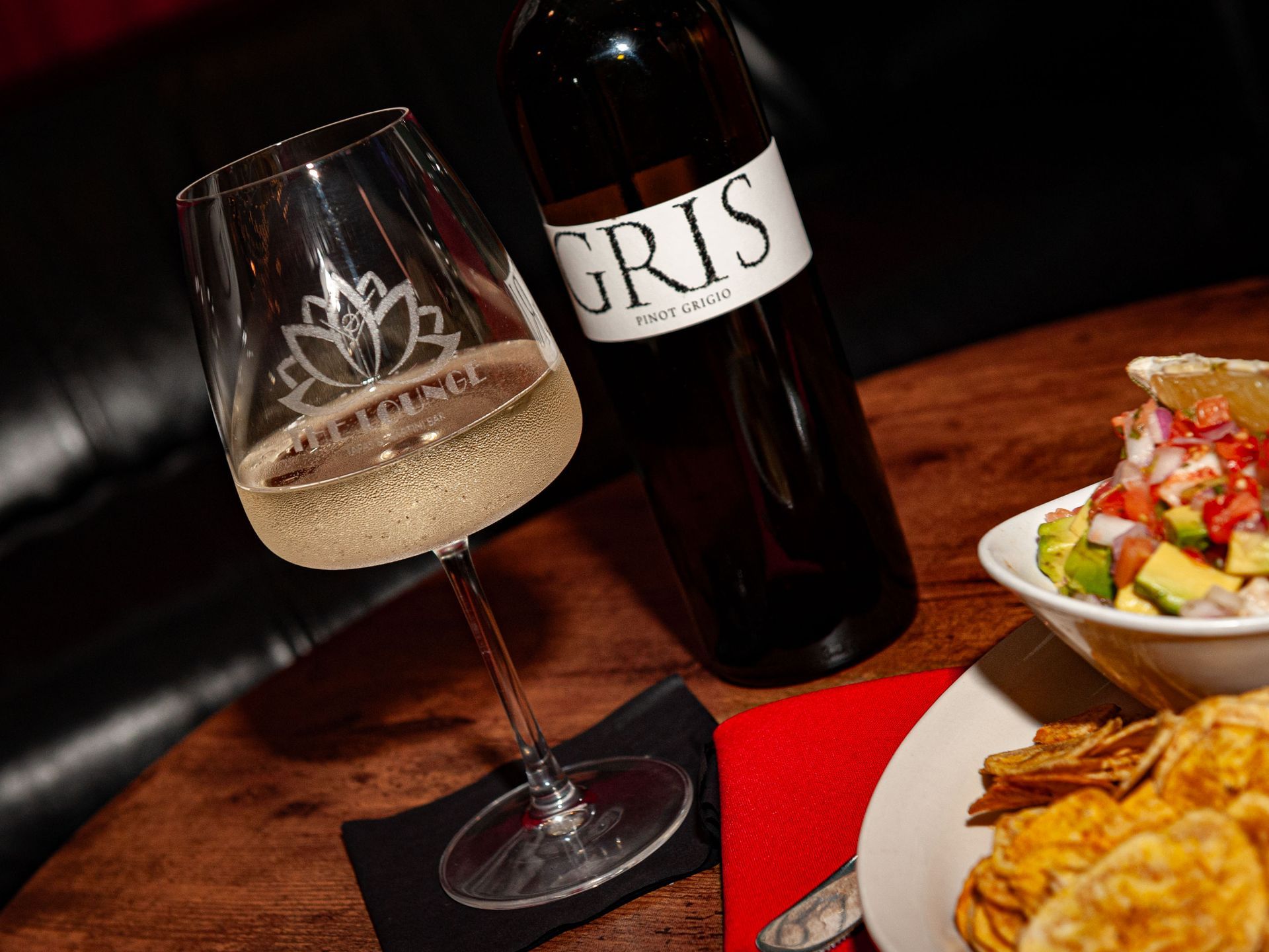 A bottle of gris wine next to a glass of wine