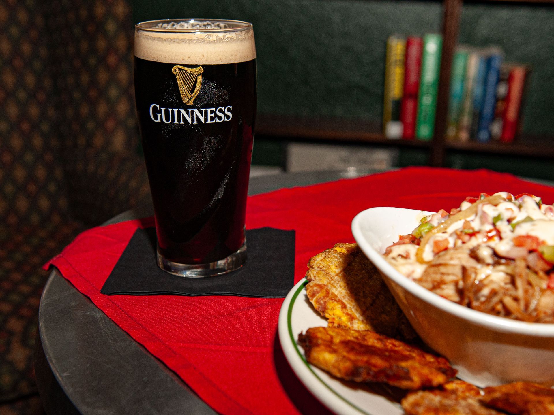 A glass of guinness sits on a table next to a bowl of food