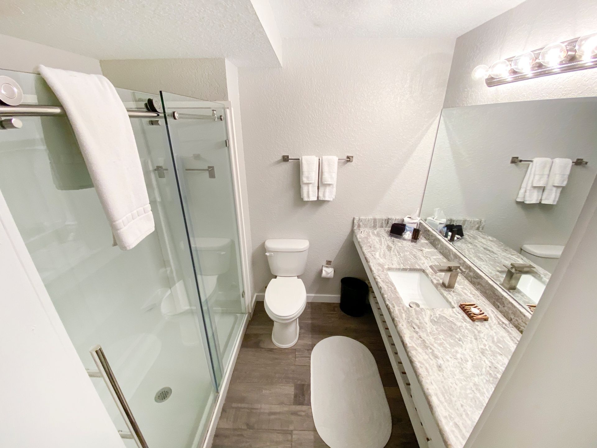 A bathroom with a toilet , sink , shower and mirror.