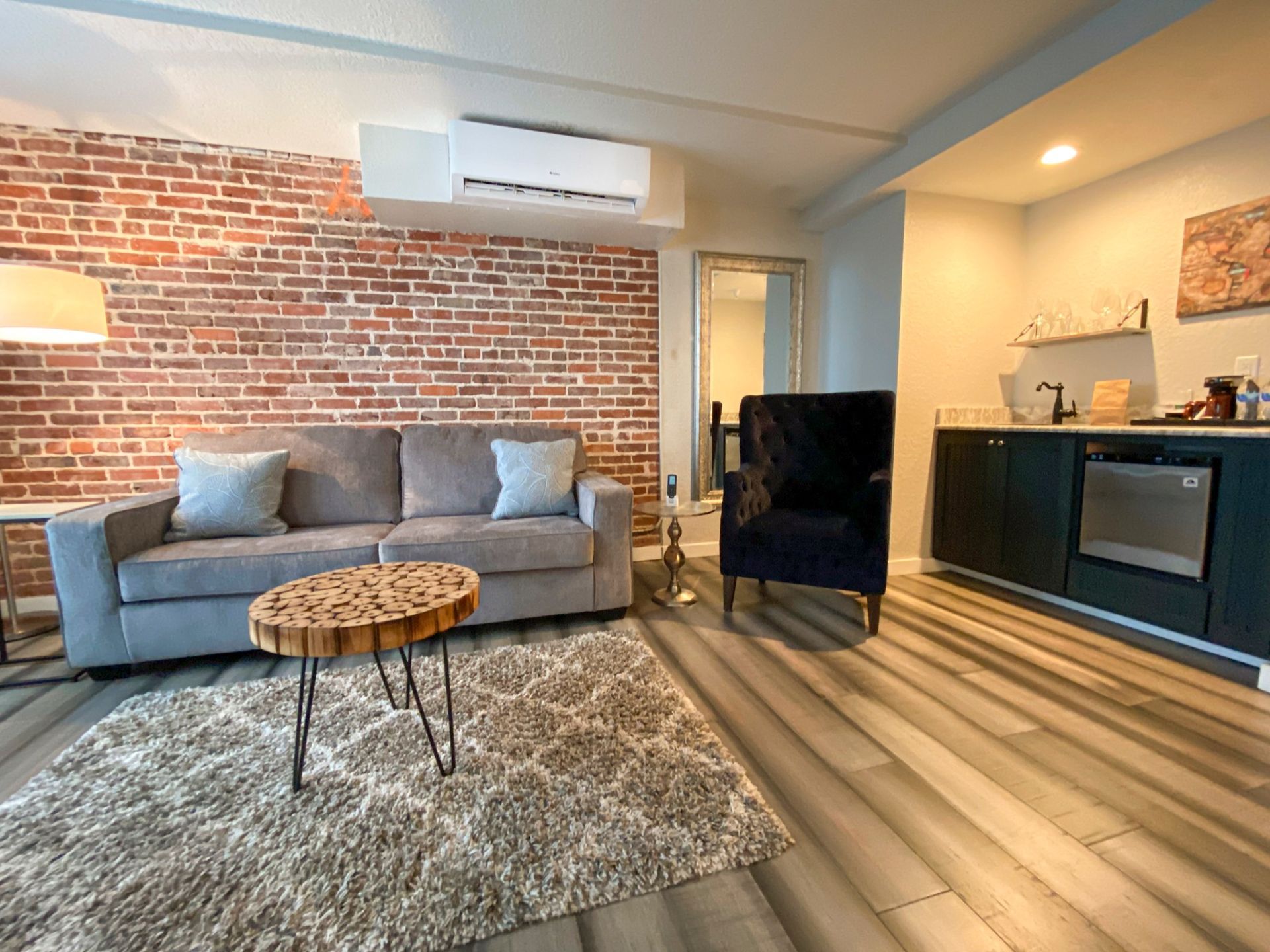 A living room with a couch , chair , table and brick wall.