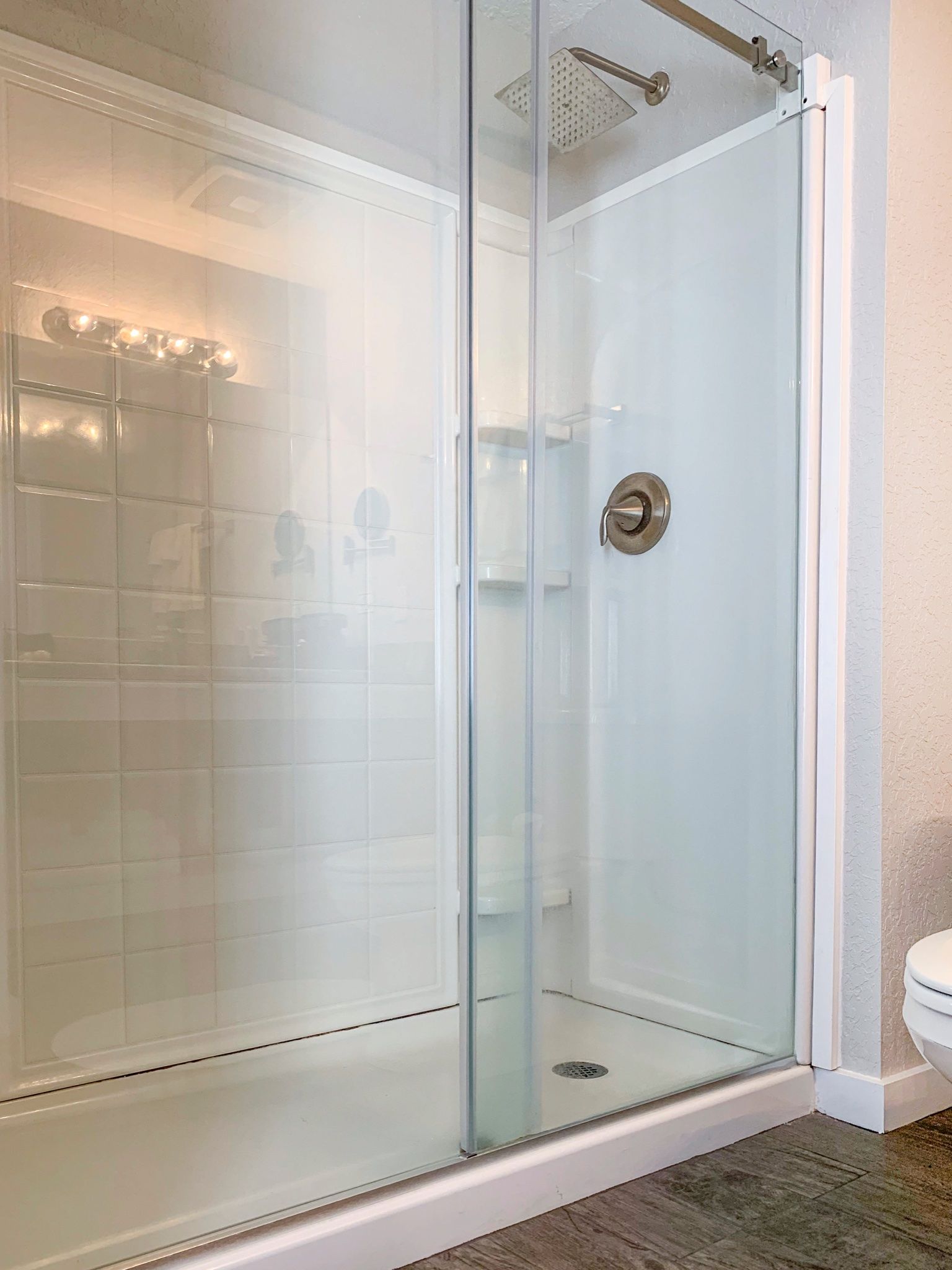 A bathroom with a walk in shower with a glass door.