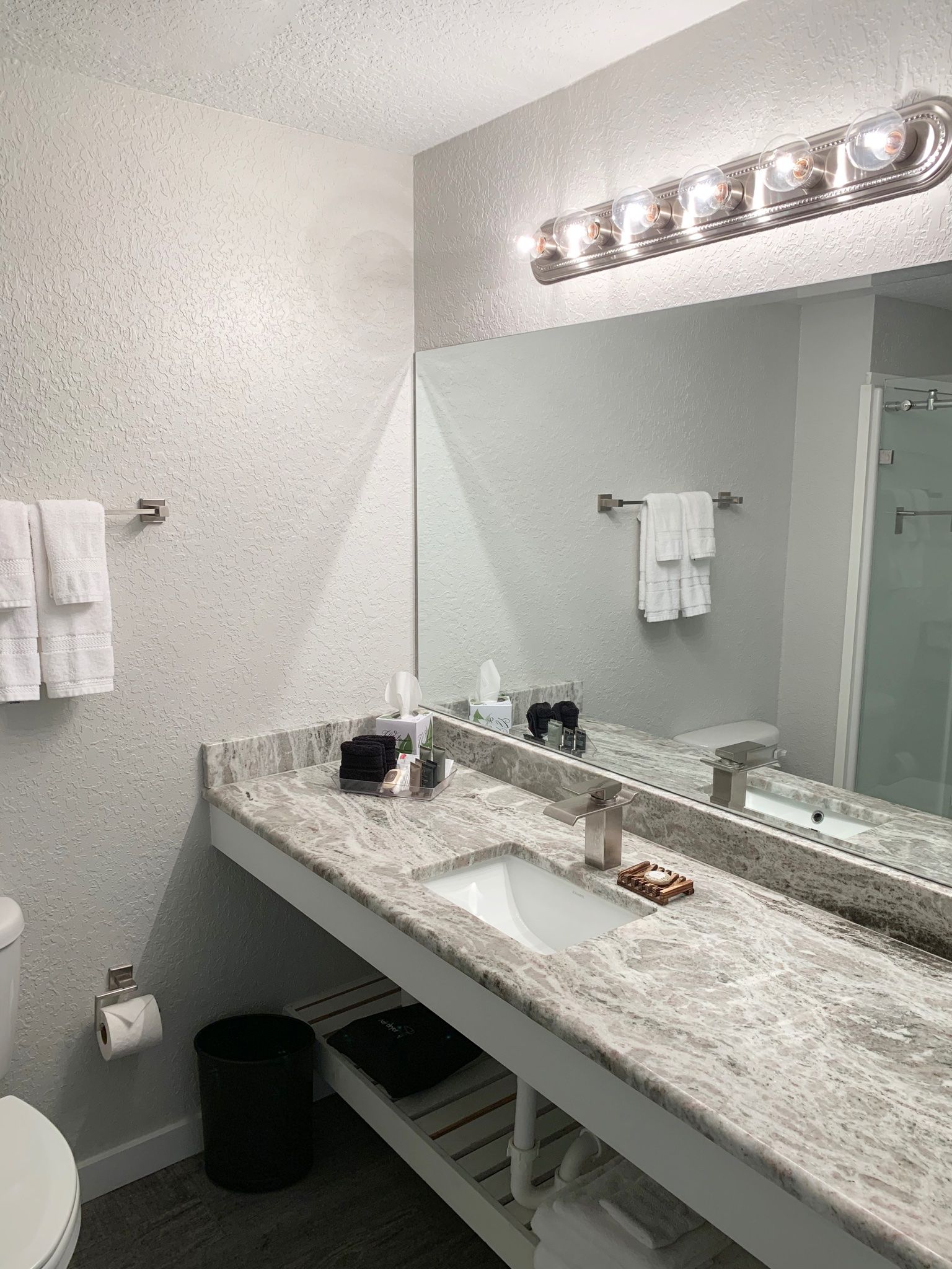 A bathroom with a sink , toilet and mirror.