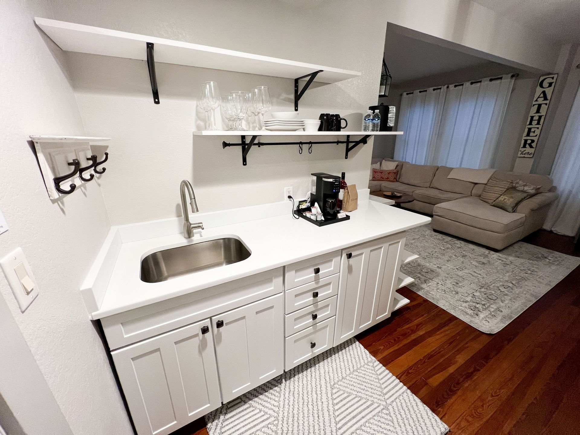 A kitchen with white cabinets and a sink in a living room.