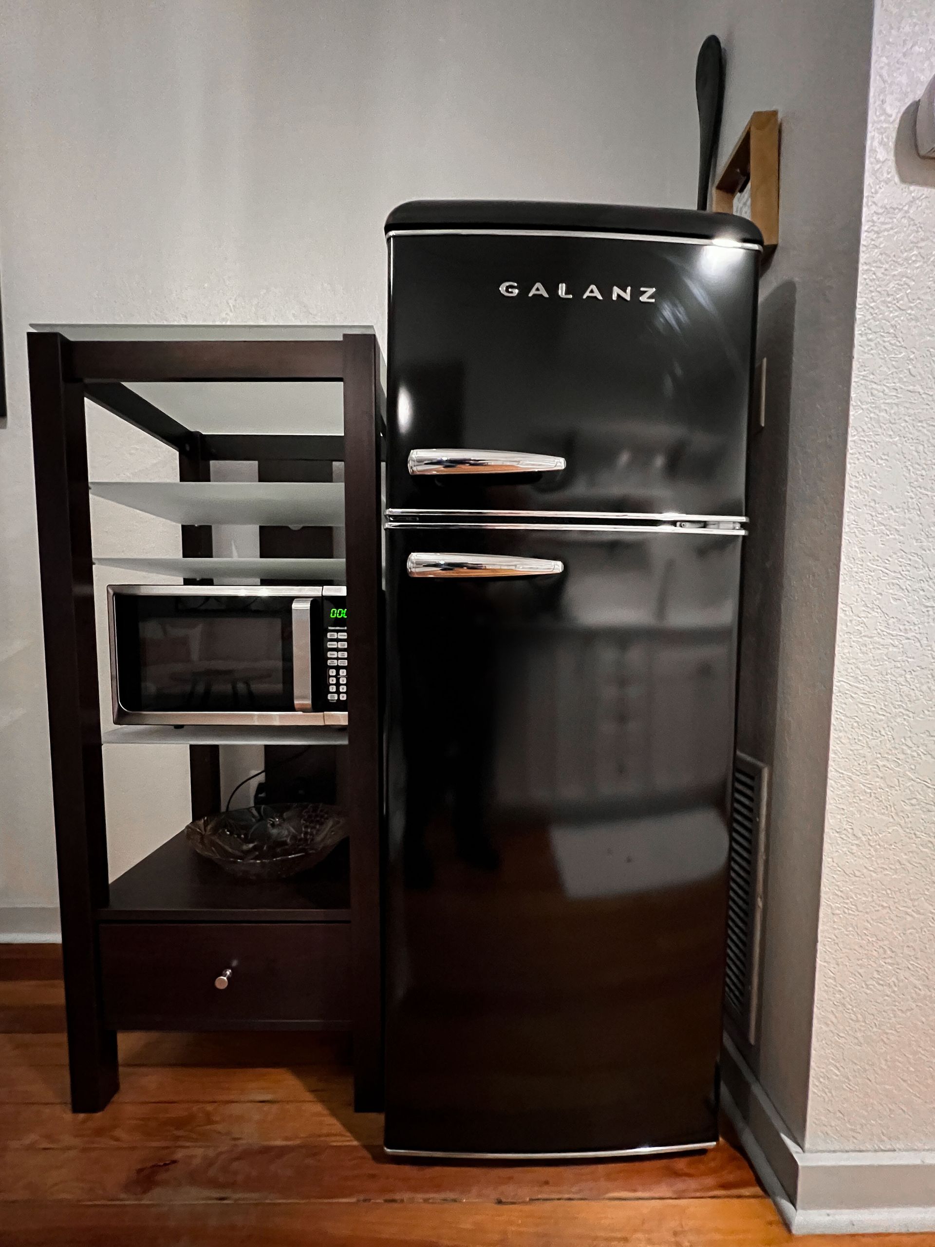 A black refrigerator is sitting next to a microwave