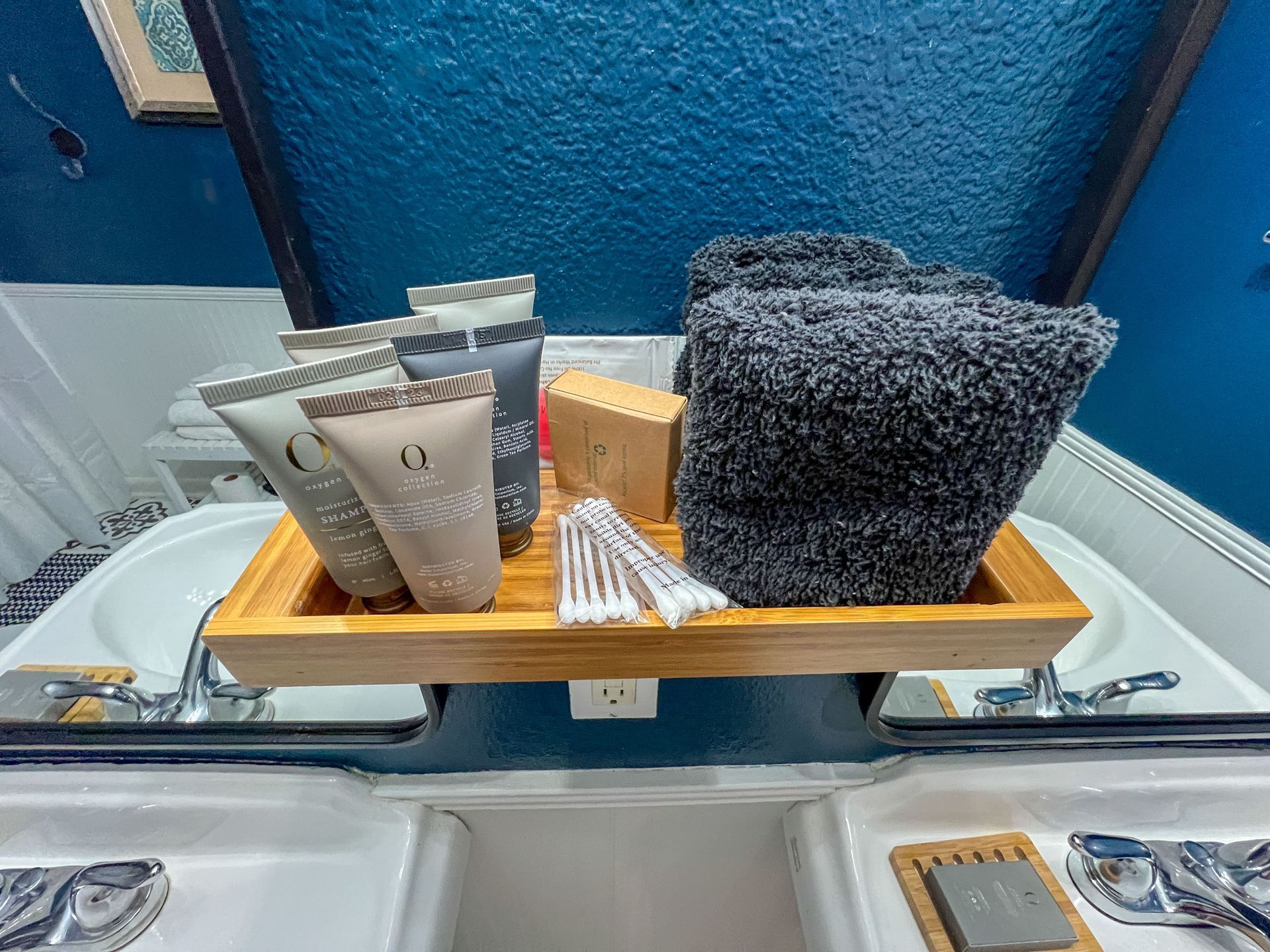 A bathroom sink with a wooden tray filled with toiletries and towels.
