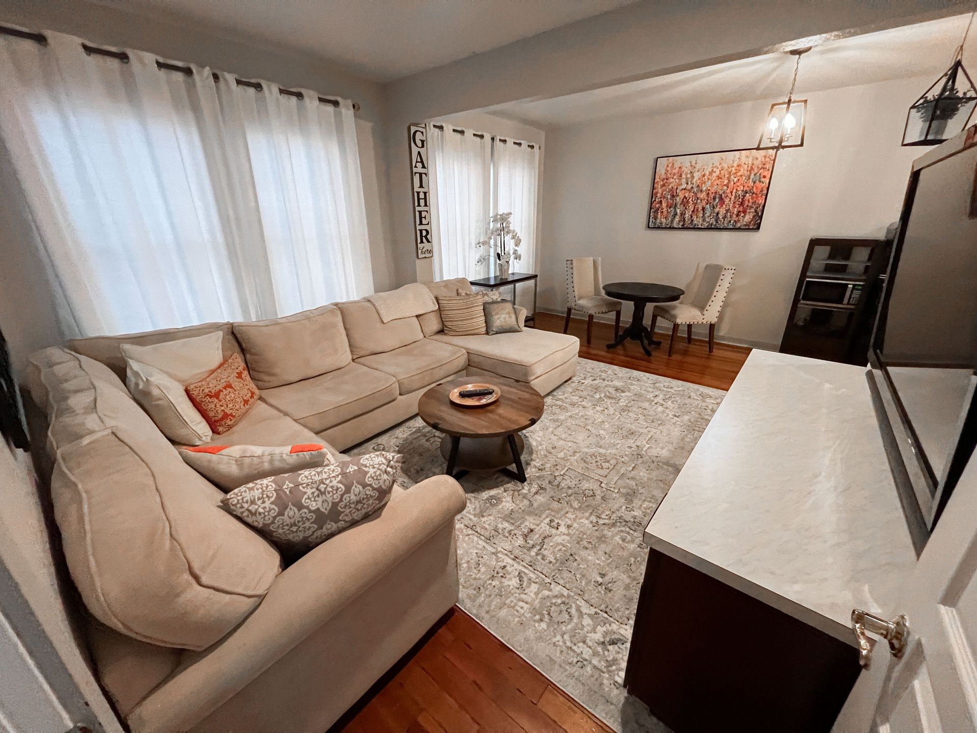 A living room with a couch , table , chairs and a television.