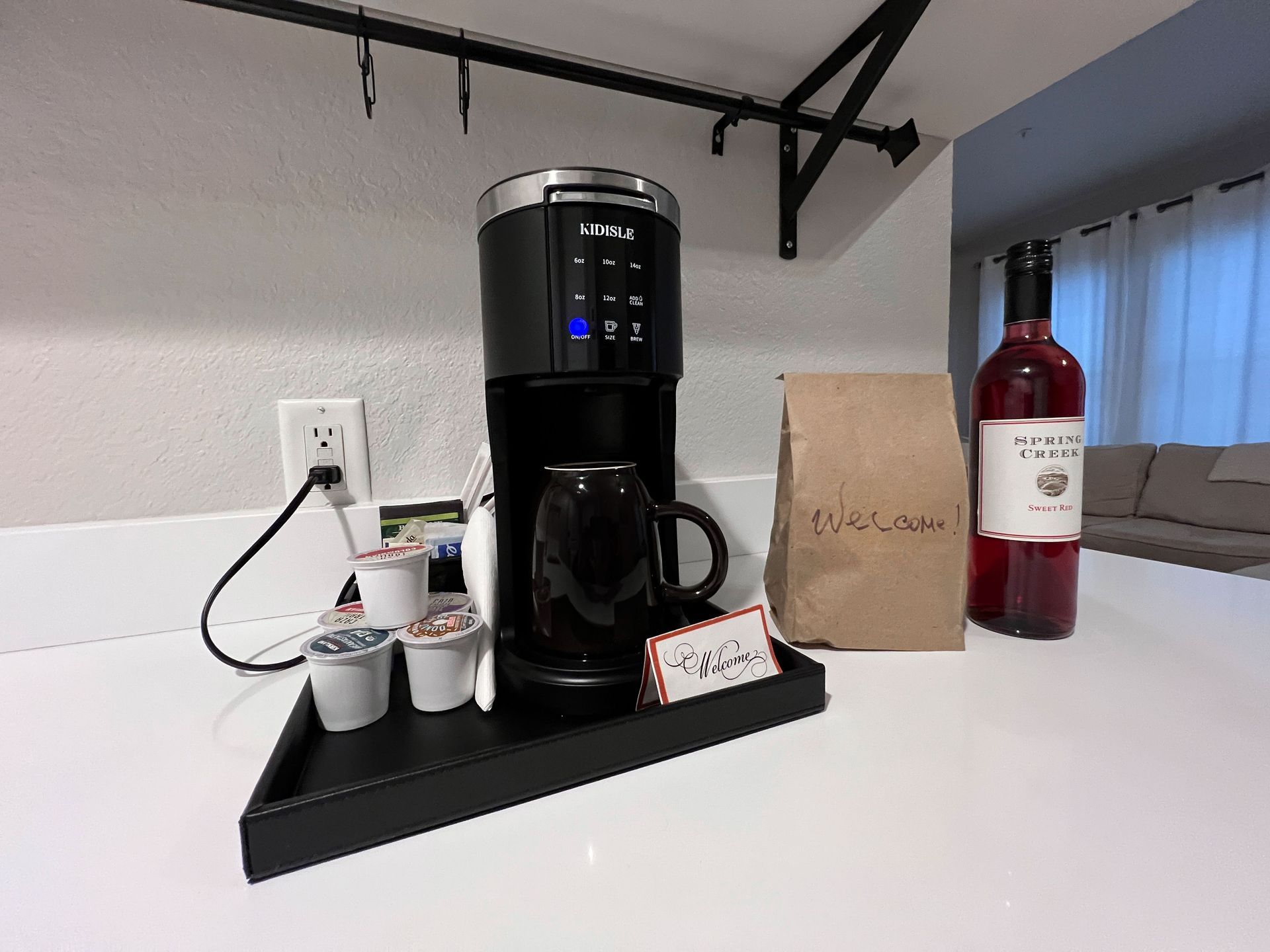 A coffee maker is sitting on a counter next to a bag of coffee and a bottle of wine.